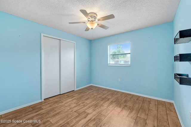 1123 Hermosa Dr, Rockledge, FL 32955 - unfurnished bedroom featuring wood finished floors, a textured ceiling, a closet, baseboards, and a ceiling fan