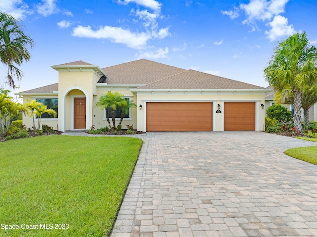 7406 Millbrook Ave, Melbourne, FL 32940 - mediterranean / spanish-style house featuring decorative driveway, a garage, a front yard, stucco siding, and a shingled roof