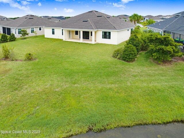 7406 Millbrook Ave, Melbourne, FL 32940 - back of property with a patio, a shingled roof, stucco siding, a yard, and a residential view