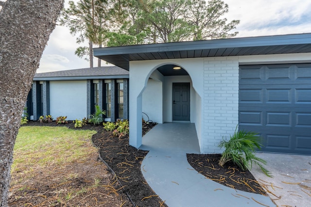306 Harvey Ave NE, Palm Bay, FL 32907 - doorway to property with an attached garage, brick siding, and stucco siding