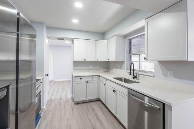 306 Harvey Ave NE, Palm Bay, FL 32907 - kitchen with appliances with stainless steel finishes, a sink, light stone counters, light wood finished floors, and white cabinets