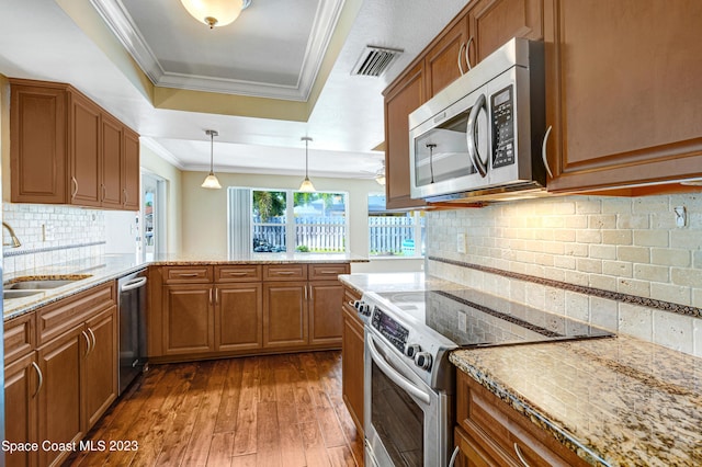 1455 Centaurus Ct, Merritt Island, FL 32953 - kitchen featuring stainless steel appliances, a raised ceiling, crown molding, and brown cabinetry