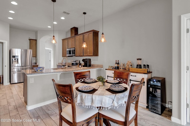 4070 Sage Brush Cir, Melbourne, FL 32901 - dining area with wine cooler, recessed lighting, arched walkways, and light wood-style flooring