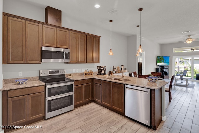 4070 Sage Brush Cir, Melbourne, FL 32901 - kitchen featuring appliances with stainless steel finishes, a peninsula, open floor plan, light stone counters, and light wood-style floors