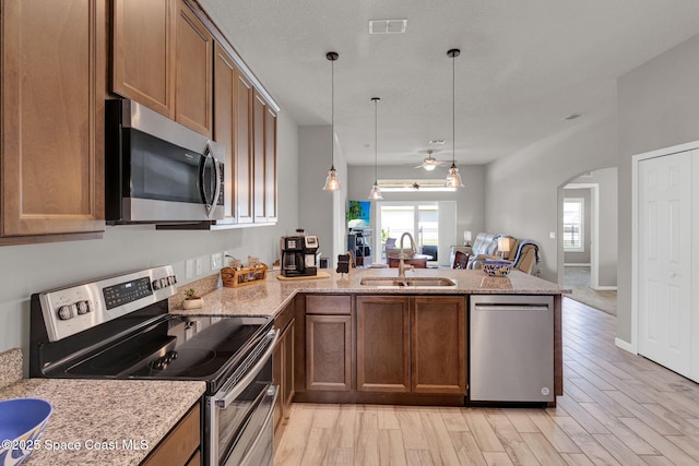 4070 Sage Brush Cir, Melbourne, FL 32901 - kitchen featuring appliances with stainless steel finishes, a peninsula, arched walkways, open floor plan, and light wood-style floors