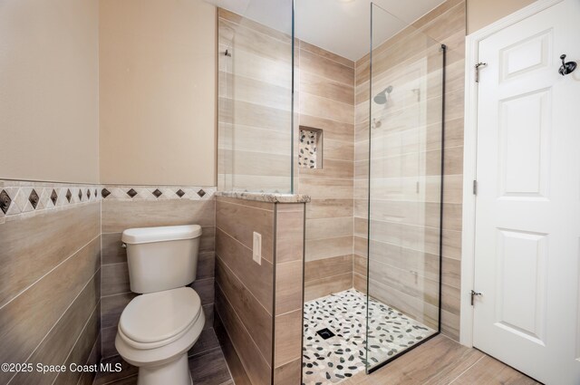 630 Seville Ct, Satellite Beach, FL 32937 - full bathroom featuring tiled shower, tile walls, wood finished floors, and wainscoting