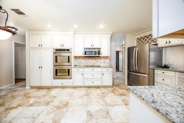 630 Seville Ct, Satellite Beach, FL 32937 - kitchen with appliances with stainless steel finishes, light stone counters, and tasteful backsplash
