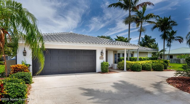 630 Seville Ct, Satellite Beach, FL 32937 - ranch-style house with a tiled roof, driveway, an attached garage, and brick siding