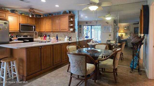 8714 Jasmine Ct, Cape Canaveral, FL 32920 - kitchen featuring appliances with stainless steel finishes, a peninsula, a ceiling fan, brown cabinetry, and recessed lighting