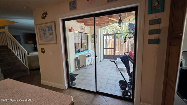8714 Jasmine Ct, Cape Canaveral, FL 32920 - doorway with a ceiling fan, light tile patterned floors, baseboards, and stairs
