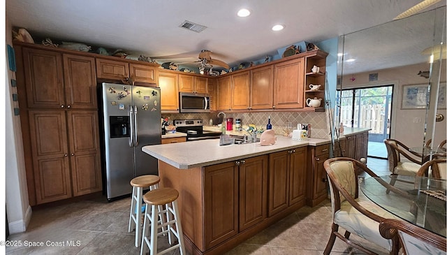8714 Jasmine Ct, Cape Canaveral, FL 32920 - kitchen with stainless steel appliances, a peninsula, open shelves, backsplash, and recessed lighting