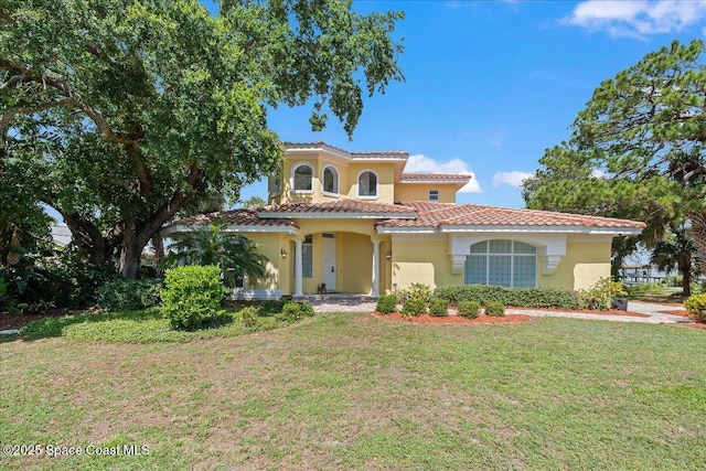 1999 S Misty Harbor Pl, Merritt Island, FL 32952 - mediterranean / spanish-style home featuring stucco siding, a front lawn, and a tile roof