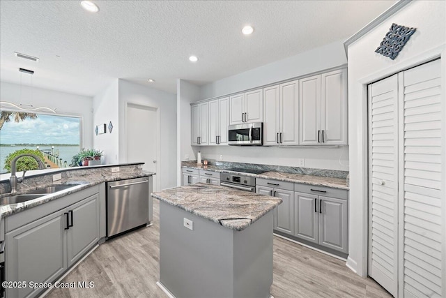 1999 S Misty Harbor Pl, Merritt Island, FL 32952 - kitchen featuring stainless steel appliances, gray cabinets, light wood-style floors, a textured ceiling, and a kitchen island