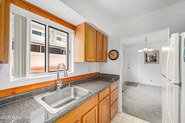 1700 Atlantic St Unit 1, Melbourne Beach, FL 32951 - kitchen featuring freestanding refrigerator, a sink, dark countertops, light colored carpet, and a chandelier