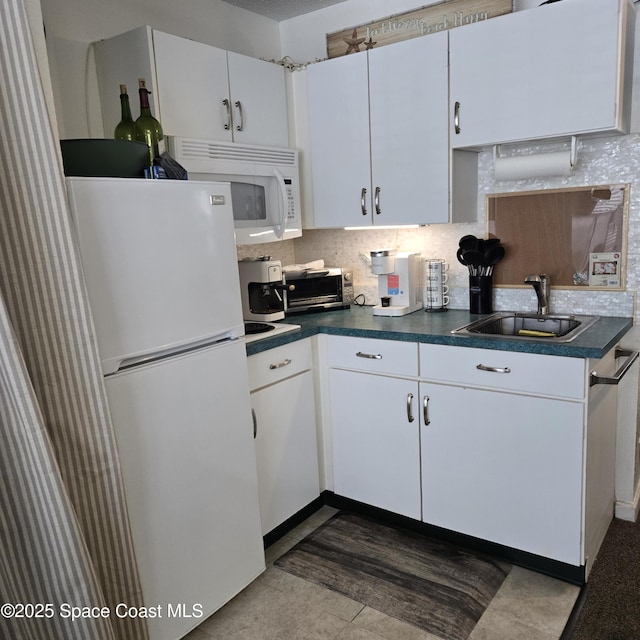 935 S Atlantic Ave Unit 234, Daytona Beach, FL 32118 - kitchen with white appliances, a sink, dark countertops, tasteful backsplash, and white cabinetry