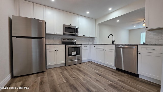 1880 Murrell Rd Unit E19, Rockledge, FL 32955 - kitchen with appliances with stainless steel finishes, decorative backsplash, light stone counters, white cabinetry, and light wood-style floors