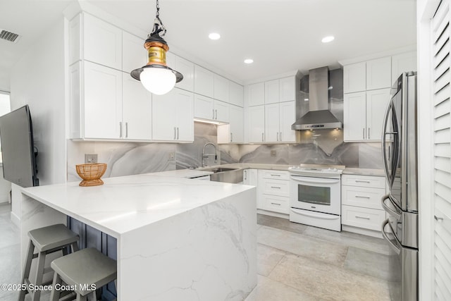 333 N Atlantic Ave Unit 333, Cocoa Beach, FL 32931 - kitchen featuring white electric stove, wall chimney range hood, freestanding refrigerator, a peninsula, and a kitchen breakfast bar