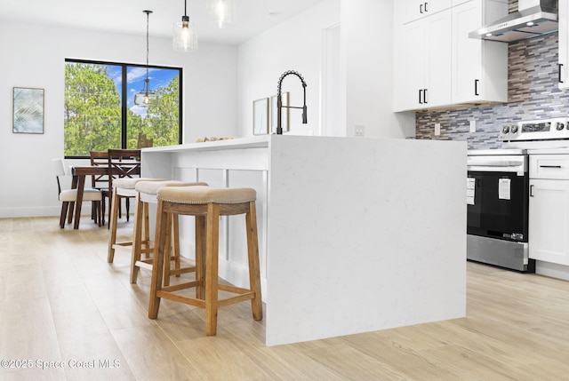 337 Fifer St SE, Palm Bay, FL 32909 - kitchen featuring stainless steel electric stove, ventilation hood, light wood-style flooring, decorative backsplash, and a breakfast bar