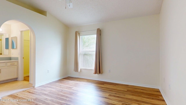 2178 Redwood Cir NE, Palm Bay, FL 32905 - empty room with arched walkways, light wood finished floors, lofted ceiling, a textured ceiling, and a ceiling fan