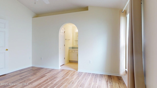 2178 Redwood Cir NE, Palm Bay, FL 32905 - unfurnished bedroom featuring vaulted ceiling, arched walkways, light wood-type flooring, connected bathroom, and baseboards