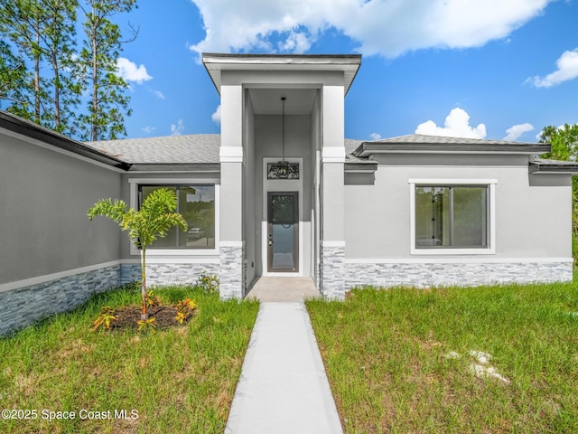 531 Higgs Ave NW, Palm Bay, FL 32907 - view of exterior entry featuring stone siding, stucco siding, and a yard