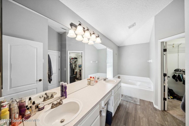 1236 Foxridge Pl, Melbourne, FL 32940 - bathroom with a walk in closet, wood finished floors, a bath, a textured ceiling, and double vanity