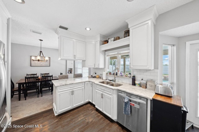 1236 Foxridge Pl, Melbourne, FL 32940 - kitchen with stainless steel dishwasher, dark wood-type flooring, a chandelier, a peninsula, and white cabinetry