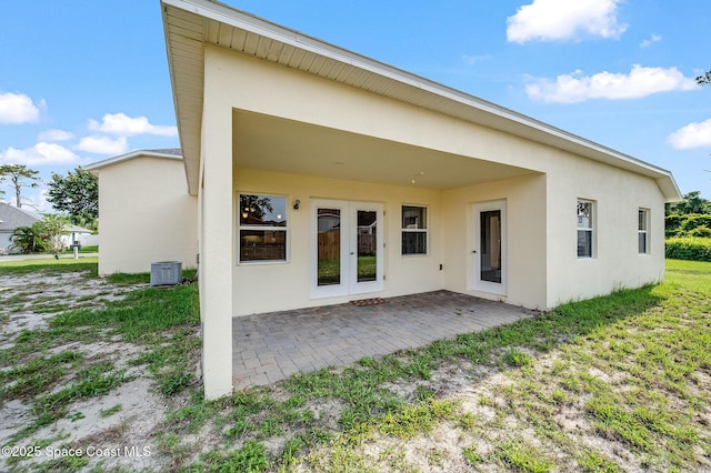 3977 Foothill Dr, Titusville, FL 32796 - rear view of house with stucco siding, a patio area, central AC, and french doors
