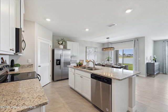 1103 Dunes Ave, Melbourne, FL 32904 - kitchen with appliances with stainless steel finishes, light tile patterned floors, an island with sink, white cabinetry, and pendant lighting
