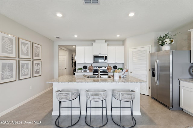 1103 Dunes Ave, Melbourne, FL 32904 - kitchen featuring stainless steel appliances, a breakfast bar area, light tile patterned floors, white cabinetry, and recessed lighting