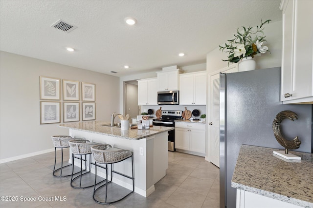 1103 Dunes Ave, Melbourne, FL 32904 - kitchen with stainless steel appliances, a kitchen breakfast bar, white cabinets, recessed lighting, and a textured ceiling