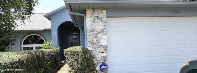 1796 Lambton Street Nw Port Malabar Unit 44, Palm Bay, FL 32907 - view of property exterior with stucco siding, a garage, stone siding, and a shingled roof