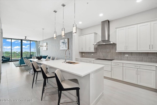 3031 Hafen Ln Unit 306, Melbourne Beach, FL 32951 - kitchen with wall chimney exhaust hood, black electric stovetop, light countertops, open floor plan, and a wall of windows