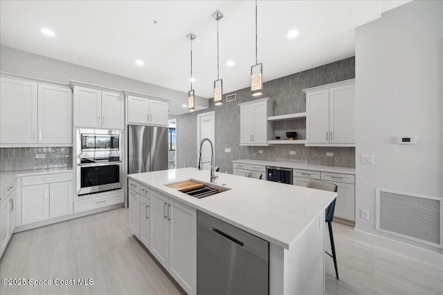 3031 Hafen Ln Unit 306, Melbourne Beach, FL 32951 - kitchen featuring stainless steel appliances, open shelves, wine cooler, tasteful backsplash, and a kitchen island with sink
