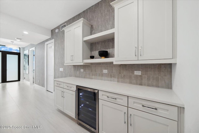 3031 Hafen Ln Unit 306, Melbourne Beach, FL 32951 - kitchen with wine cooler, open shelves, tasteful backsplash, and white cabinetry
