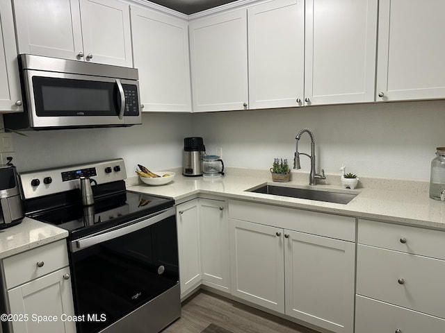 1602 Harvard Dr, Cocoa, FL 32922 - kitchen with stainless steel appliances, a sink, white cabinets, wood finished floors, and light stone countertops