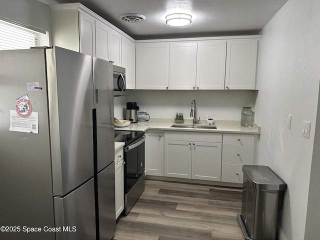 1602 Harvard Dr, Cocoa, FL 32922 - kitchen with stainless steel appliances, a sink, light countertops, white cabinetry, and dark wood finished floors