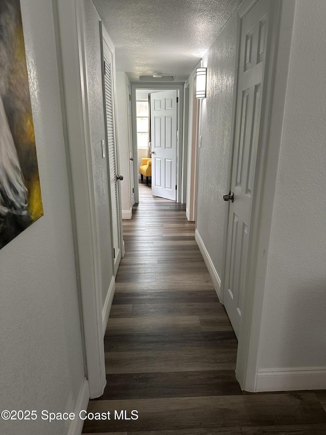 1602 Harvard Dr, Cocoa, FL 32922 - hall featuring dark wood-style flooring, a textured ceiling, baseboards, and a textured wall
