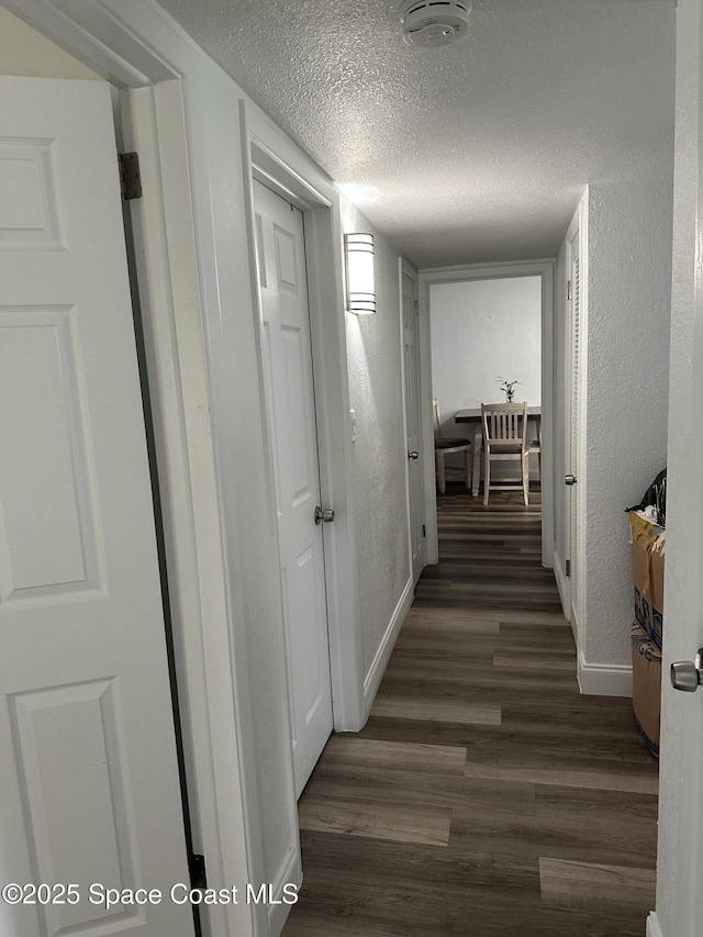 1602 Harvard Dr, Cocoa, FL 32922 - hallway featuring baseboards, a textured ceiling, dark wood-style floors, and a textured wall