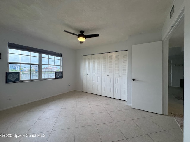 933 Sonesta Ave NE Unit 208, Palm Bay, FL 32905 - unfurnished bedroom with light tile patterned floors, ceiling fan, a closet, and a textured ceiling