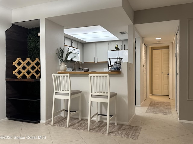 933 Sonesta Ave NE Unit 208, Palm Bay, FL 32905 - kitchen featuring white appliances, light tile patterned flooring, a breakfast bar, and a peninsula