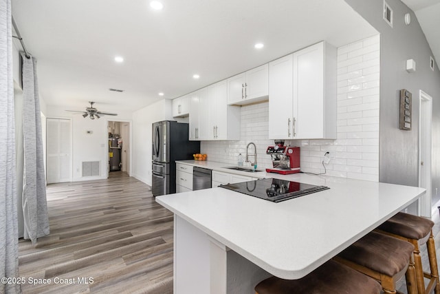 813 Laurel Dr, Rockledge, FL 32955 - kitchen with a sink, appliances with stainless steel finishes, light countertops, a kitchen bar, and light wood-style floors