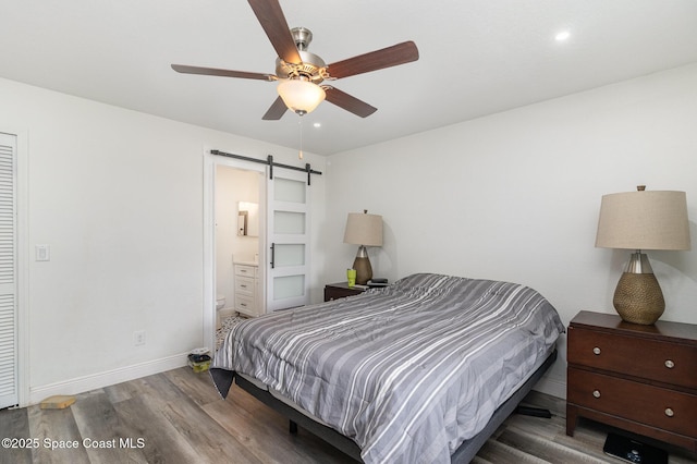 813 Laurel Dr, Rockledge, FL 32955 - bedroom featuring a barn door, wood finished floors, baseboards, ensuite bathroom, and ceiling fan