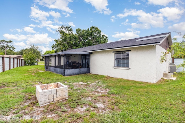 813 Laurel Dr, Rockledge, FL 32955 - back of house featuring a sunroom, stucco siding, a yard, and a fire pit
