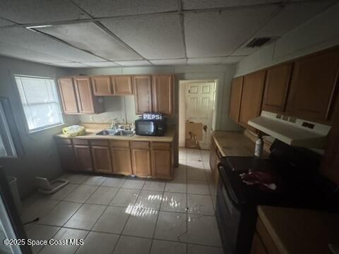 1236 Jackson St, Cocoa, FL 32922 - kitchen with a sink, under cabinet range hood, black microwave, a drop ceiling, and brown cabinetry