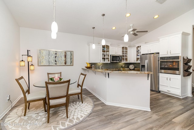 142 Ocean Garden Ln, Cape Canaveral, FL 32920 - kitchen featuring stainless steel appliances, a peninsula, glass insert cabinets, tasteful backsplash, and white cabinetry