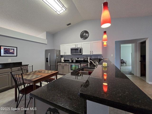 1150 Ida Way, Melbourne, FL 32940 - kitchen featuring appliances with stainless steel finishes, light tile patterned flooring, dark stone counters, a textured ceiling, and white cabinets