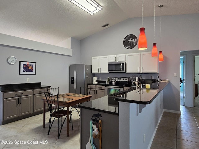1150 Ida Way, Melbourne, FL 32940 - kitchen featuring appliances with stainless steel finishes, light tile patterned flooring, high vaulted ceiling, dark countertops, and a peninsula