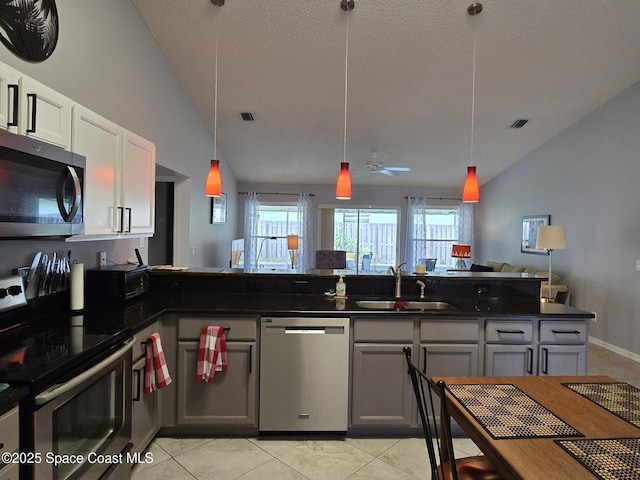 1150 Ida Way, Melbourne, FL 32940 - kitchen featuring stainless steel appliances, open floor plan, vaulted ceiling, light tile patterned floors, and a textured ceiling