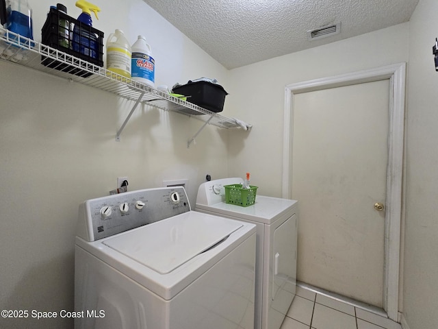 1150 Ida Way, Melbourne, FL 32940 - laundry area featuring separate washer and dryer, a textured ceiling, and light tile patterned floors